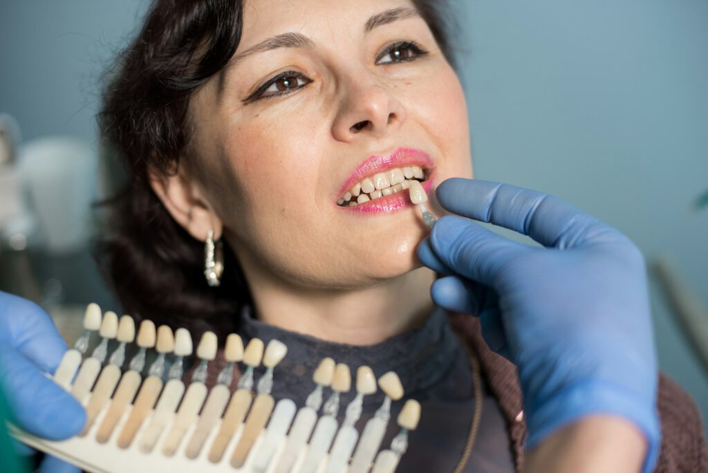 woman in dental clinic office. Dentist checking and selecting colour of the teeth. Dentistry